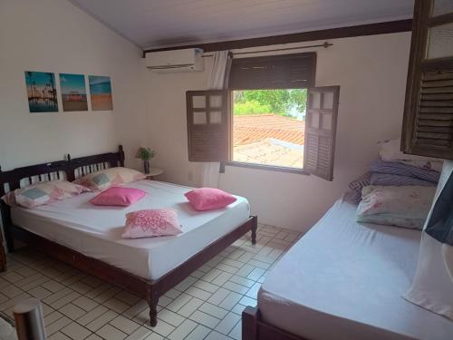 two twin beds in a room with a window at Casa Da Mari - Praia da Penha in Vera Cruz de Itaparica