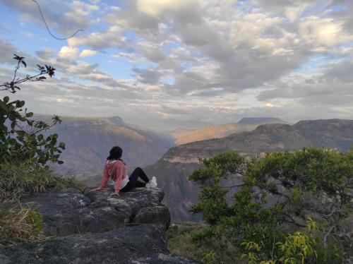 a person sitting on a rock looking at the grand canyon at Mirador Escondido del Chicamocha a 22km de Barichara in Villanueva