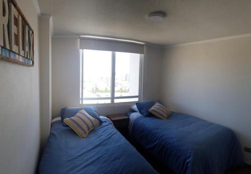 2 camas en una habitación pequeña con ventana en Departamento Viña del mar en Viña del Mar