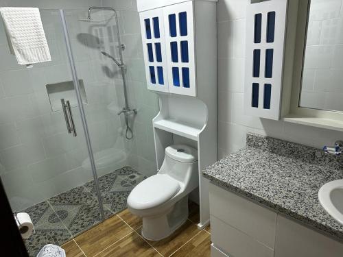 a white bathroom with a toilet and a shower at Aparta Hotel Esa Buya in San Fernando de Monte Cristi