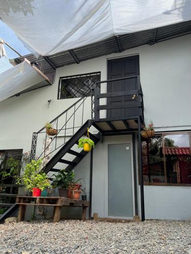 a white house with a staircase and a door at SelvaToSleep in Quepos