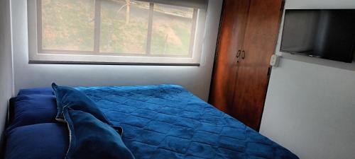 a bedroom with a blue bed with a window at Casa cerca al centro de la ciudad cupo para 6 personas in Manizales