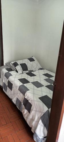 uma cama com uma colcha preta e branca num quarto em Casa cerca al centro de la ciudad cupo para 6 personas em Manizales