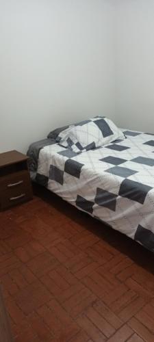 a bed with a black and white comforter and a night stand at Casa cerca al centro de la ciudad cupo para 6 personas in Manizales
