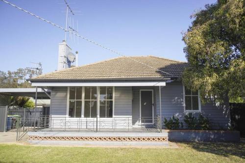a blue house with a porch and a tree at Shepparton House in Shepparton