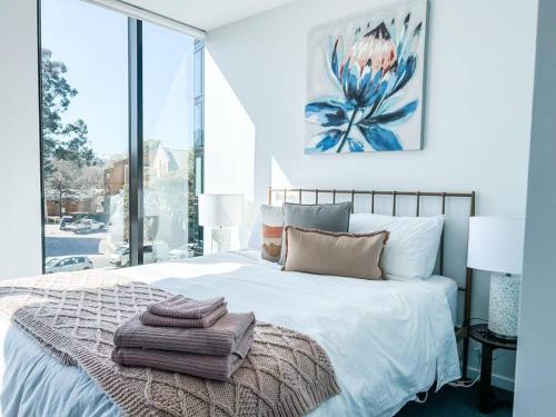 a bedroom with a white bed with a large window at Metropol - CBD pool Sleeps 7 in Canberra