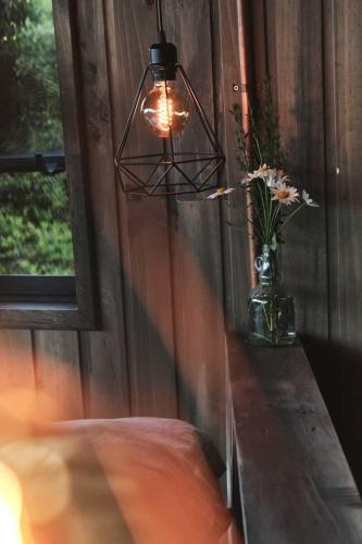 a lamp and a vase with flowers on a table at MA PU LODGE Futaleufu in Futaleufú