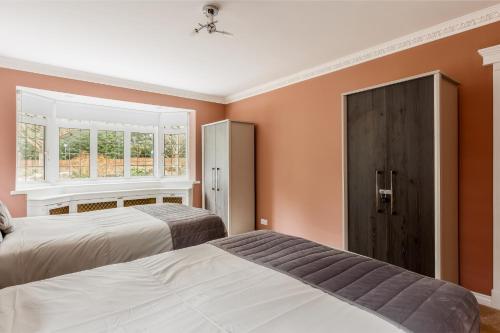 twee bedden in een slaapkamer met oranje muren bij Traditional Family House Near Beach -Great Garden! in Bournemouth