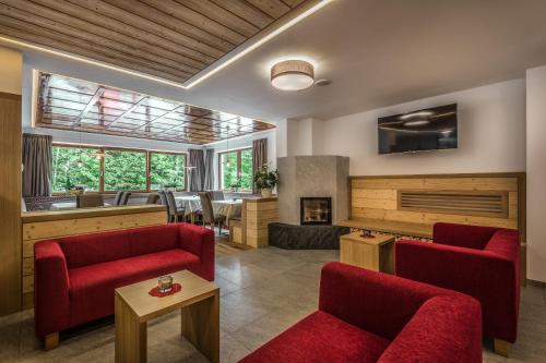 a living room with two red chairs and a fireplace at Hotel Miramonti Badia in Badia