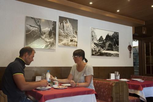 
a man and a woman sitting at a table at Hotel Garni dello Sportivo in Madonna di Campiglio
