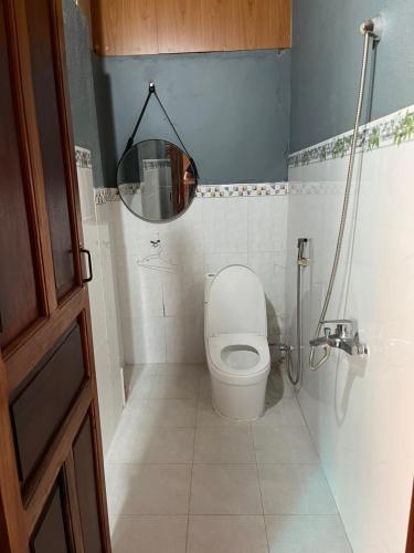 a small bathroom with a toilet and a mirror at Nhà Sàn Bên Suối in Buôn Ðũng