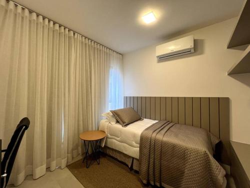 um quarto com uma cama, uma mesa e uma janela em Noroeste, requinte e bom gosto em Brasília