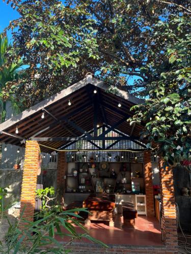 a patio with a table under a wooden roof at Nhà Sàn Bên Suối in Buôn Ðũng