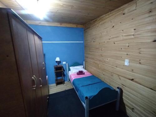 Cette petite chambre comprend un lit et un mur en bois. dans l'établissement Depto Arianna, à Los Antiguos