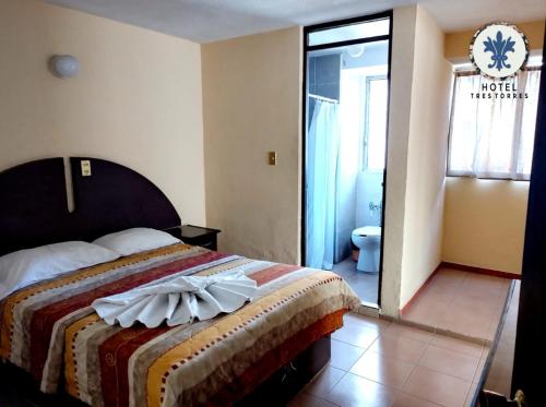 1 dormitorio con 1 cama con reloj en la pared en Hotel Tres Torres en Morelia