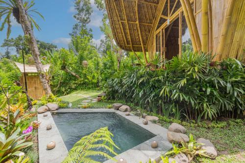 una pequeña piscina en medio de un jardín en Arcada Bali Bamboo House en Sidemen