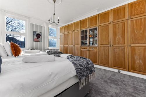 a bedroom with two beds and wooden cabinets at Peaceful and Radiant 3BR Flat in London