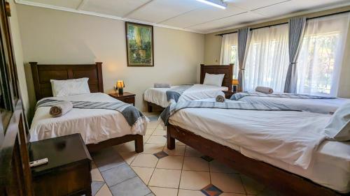a bedroom with two beds and a window at Room in Villa - Zambezi Family Lodge - Leopard Room in Victoria Falls