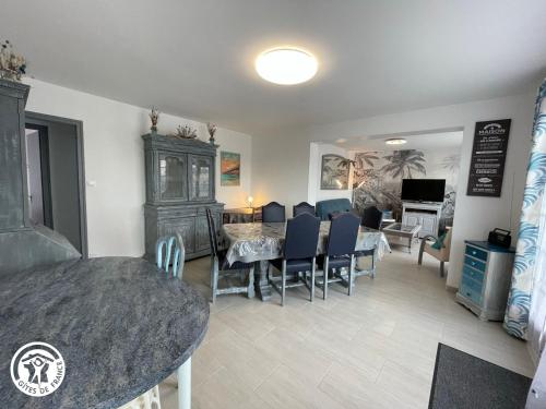 une salle à manger et un salon avec une table et des chaises dans l'établissement Maison proche plage avec jardin, prêt vélos, internet et espace lingerie - FR-1-426-545, à Saint-Hilaire-de-Riez