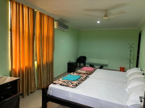 1 dormitorio con 1 cama grande y cortina de color naranja en PRARTHANA RESIDENCY, en Attingal