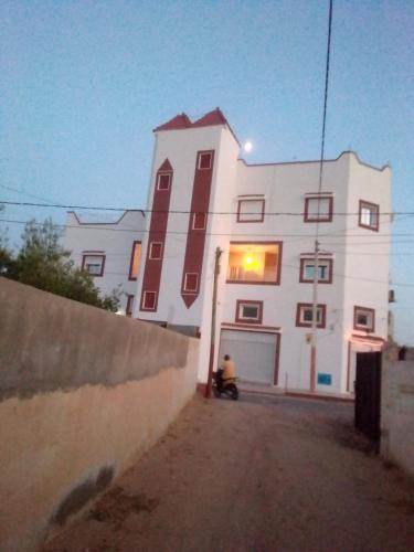 a white building with a motorcycle parked in front of it at Elmoubaraka in Tataouine