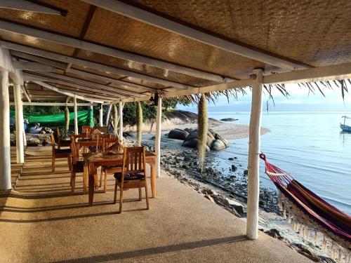a restaurant with a table and chairs and the ocean at Last Hammock Beach Resort in Ko Phangan
