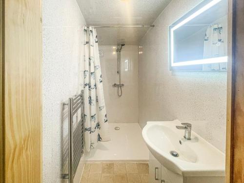 a white bathroom with a sink and a shower at Langston Farm Chalet in Shillingstone