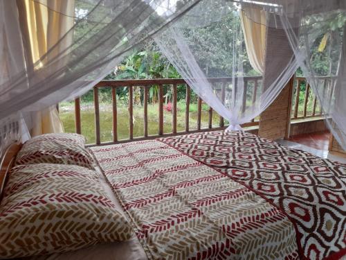 łóżko w zasłoniętej werandzie z oknem w obiekcie Hostal Ariantiy w mieście Pepino