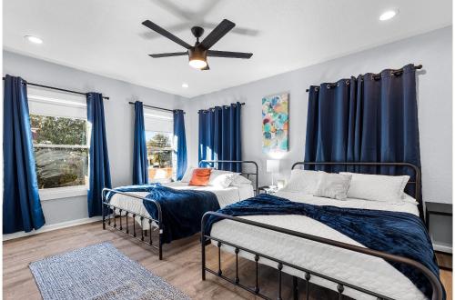 Dos camas en una habitación con cortinas azules. en Inviting 4BR2.5BA Downtown Home with Ample Space, en San Antonio