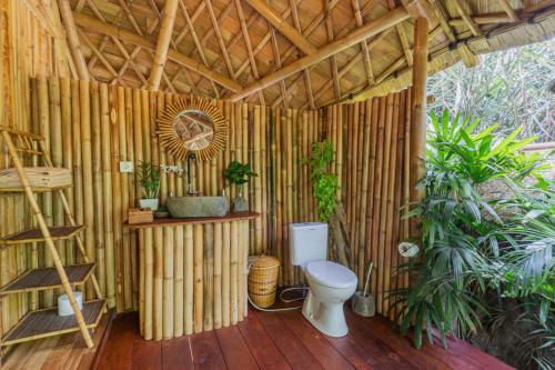 Baño de madera con aseo en una pared de bambú en Arcada Bali Bamboo House en Sidemen