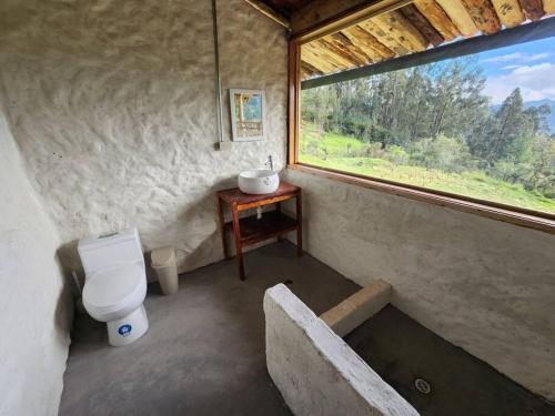 a small bathroom with a toilet and a window at Hermosa y Nueva Cabaña de campo - La Candelaria Farm House in Cuenca