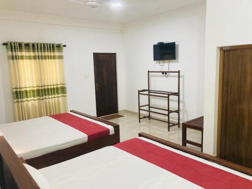 a hotel room with two beds and a television at Nugasewana Guest in Anuradhapura