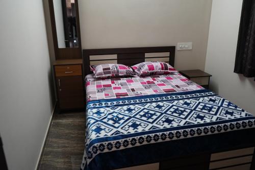 a bedroom with a bed with a quilt on it at Shobha Comforts in Chikmagalūr