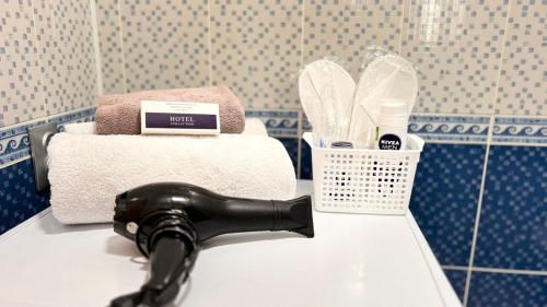 a black hair dryer on a sink in a bathroom at Светлая квартира , с видом на набережную. in Astana