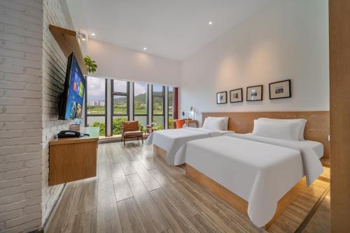 2 Betten in einem Hotelzimmer mit einem TV in der Unterkunft Wuyu Hotel Chongqing Jinyun Mountain Southwest University in Chongqing
