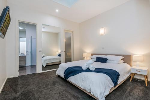 een witte slaapkamer met een groot bed en een spiegel bij Serpentine Park on View in Bendigo