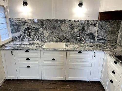 a white kitchen with a sink and a counter at Comfy Queenslander Cottage in Brisbane