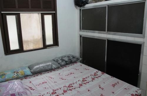 a bed in a room with two windows at Casa de Alvenaria- Mauá in Mauá
