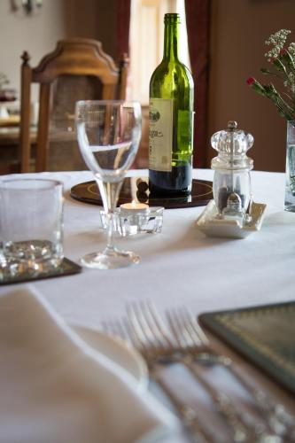 a white table with a bottle of wine and glasses at Whitehouse Country House in Saint Boswells