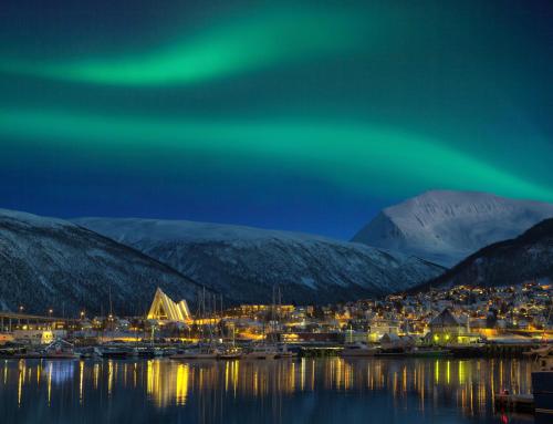Una aurora brilla sobre un pequeño puerto de noche en Lovely apartment in Tromsø city centre en Tromsø