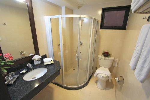 a bathroom with a shower and a toilet and a sink at The Dawin Hotel in Bangkok