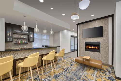 a lobby with a bar with chairs and a fireplace at TownePlace Suites by Marriott Sudbury in Sudbury