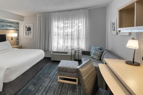 a hotel room with a bed and a couch at TownePlace Suites by Marriott Sudbury in Sudbury