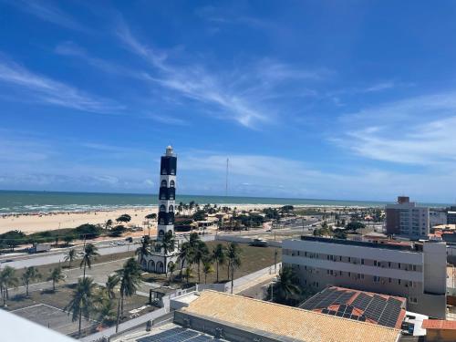 a lighthouse on the beach next to a city at Studio Completo, Condominio Grand Smart Residence in Aracaju