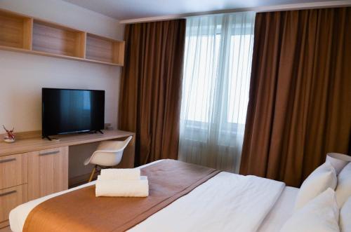um quarto de hotel com uma cama e uma televisão de ecrã plano em Yes Апарт-отель em Astana
