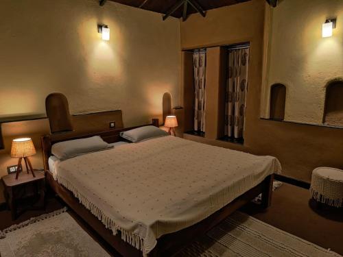 a bedroom with a bed and two lamps and a window at Khirni House in Māndu
