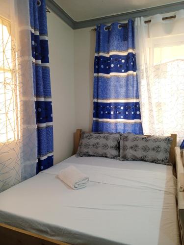 a bed in a room with blue and white curtains at Jackie homes in Mombasa