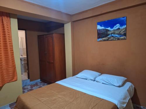 ein Schlafzimmer mit einem Bett mit einem Schrank und einem Bild an der Wand in der Unterkunft Montañero Hostel II in Huaraz