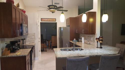 a kitchen with a sink and a counter with chairs at Abode Villas in Cape Coral