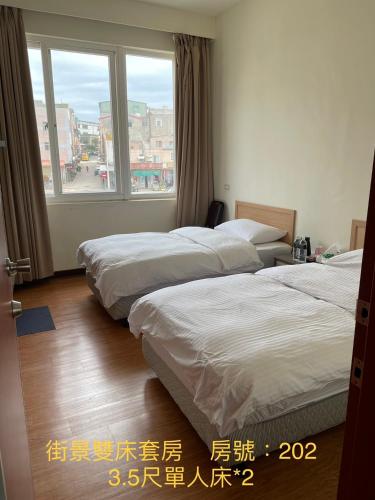two beds in a room with a window at 馬港驛站 Oldharbor Hostel in Nangan